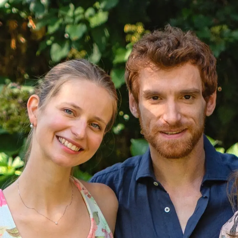 Carolina e Alberto, sorridenti, davanti a una siepe verde