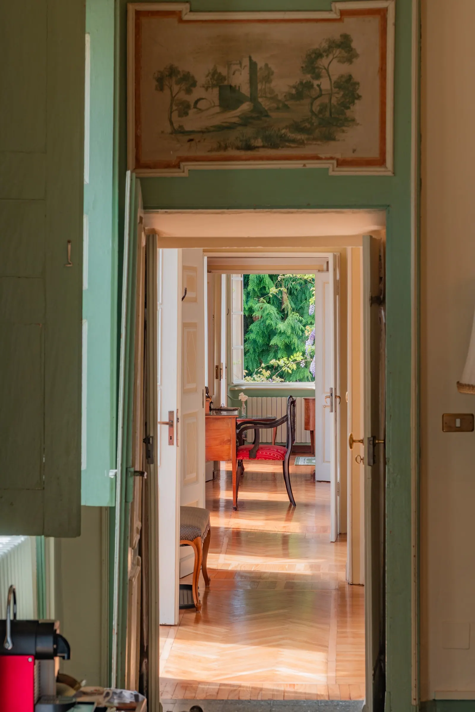 L’enfilade delle stanze vista dalla porta verde, con la sovrapporta dipinta sopra, fino alla finestra sul giardino