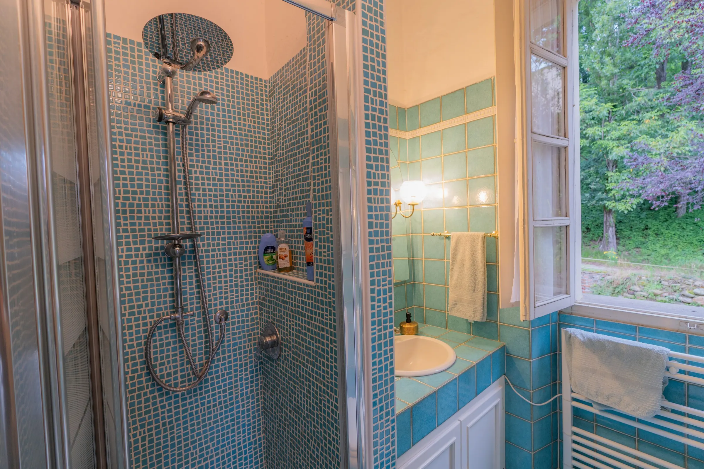 La doccia del bagno turchese, rivestita a mosaico, con il soffione tondo