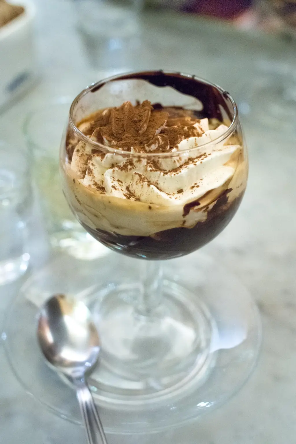 Un bicerin nel bicchiere a calice, con il cioccolato sul fondo e la crema spolverata di cacao