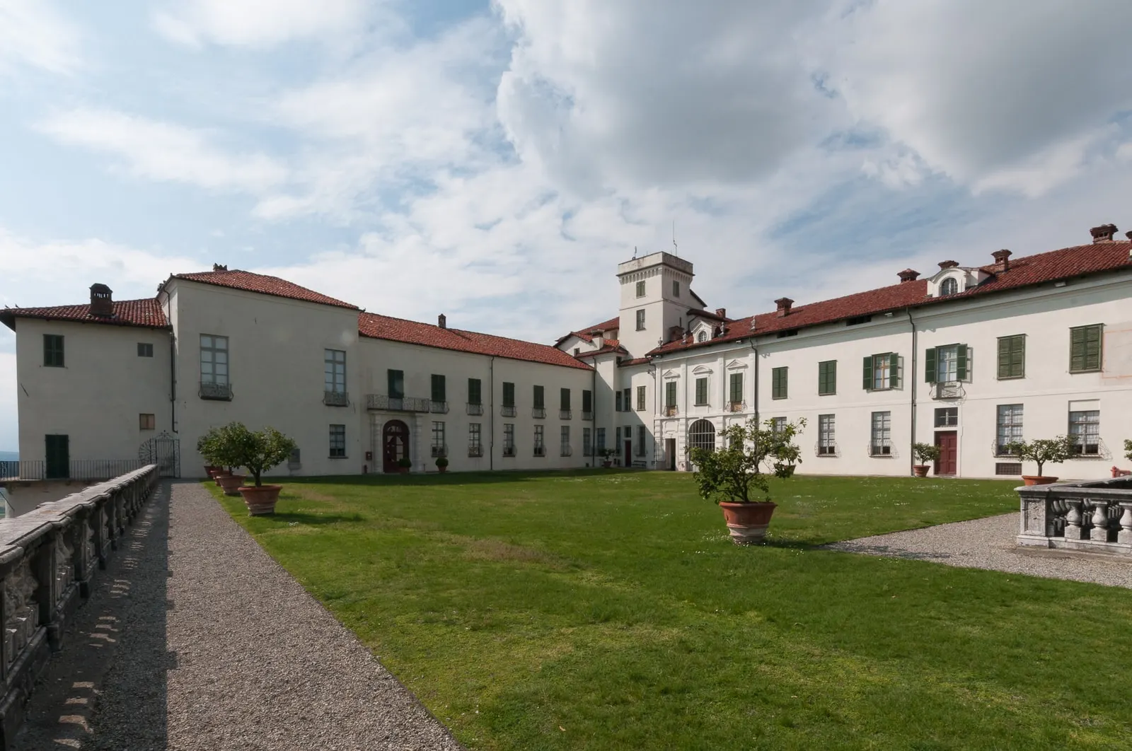 Il cortile del Castello di Masino, con il prato, i vasi di agrumi e le facciate chiare dalle persiane verdi