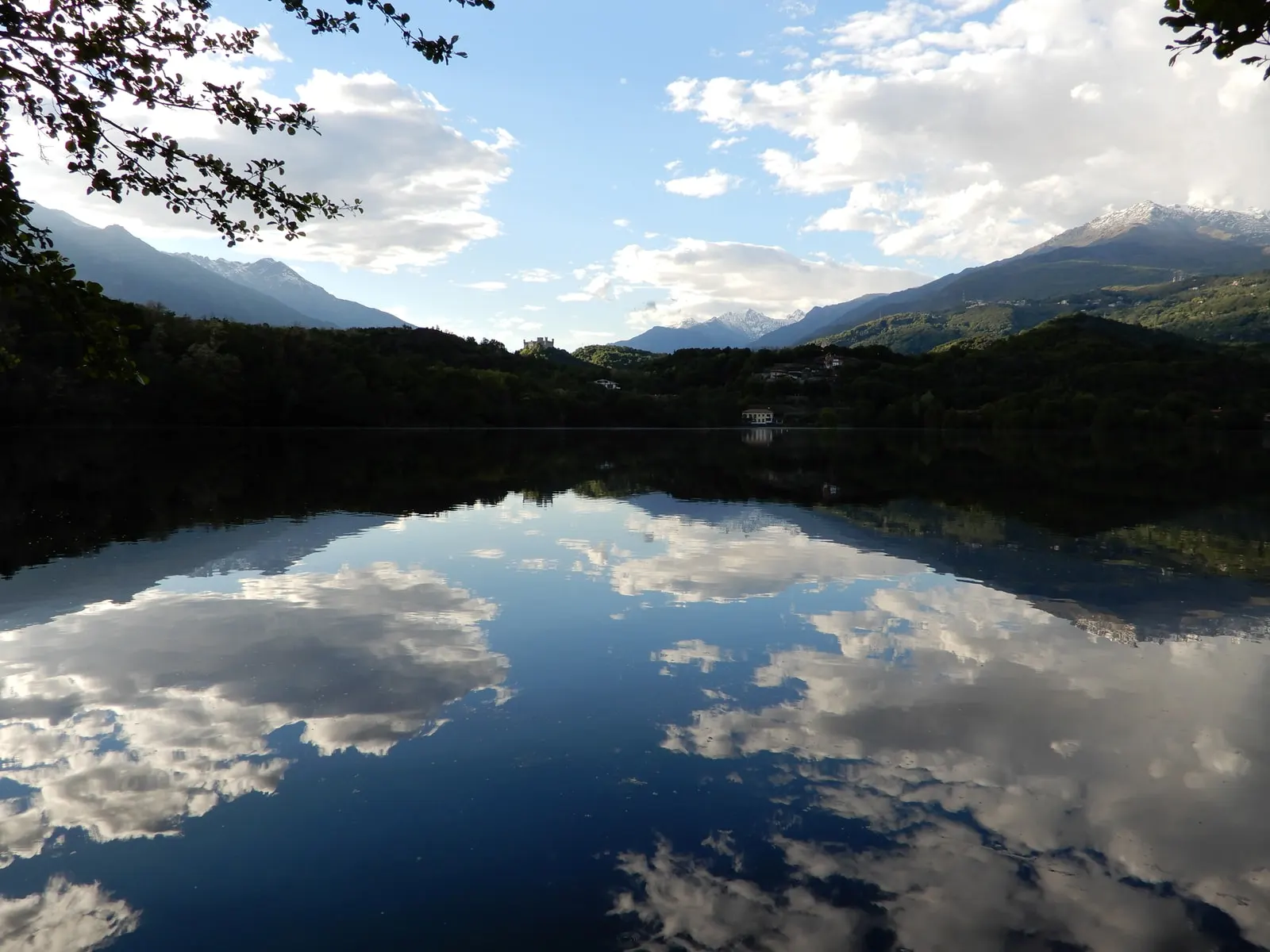 Il Lago Sirio fra i boschi, con le nuvole e le montagne riflesse nell’acqua